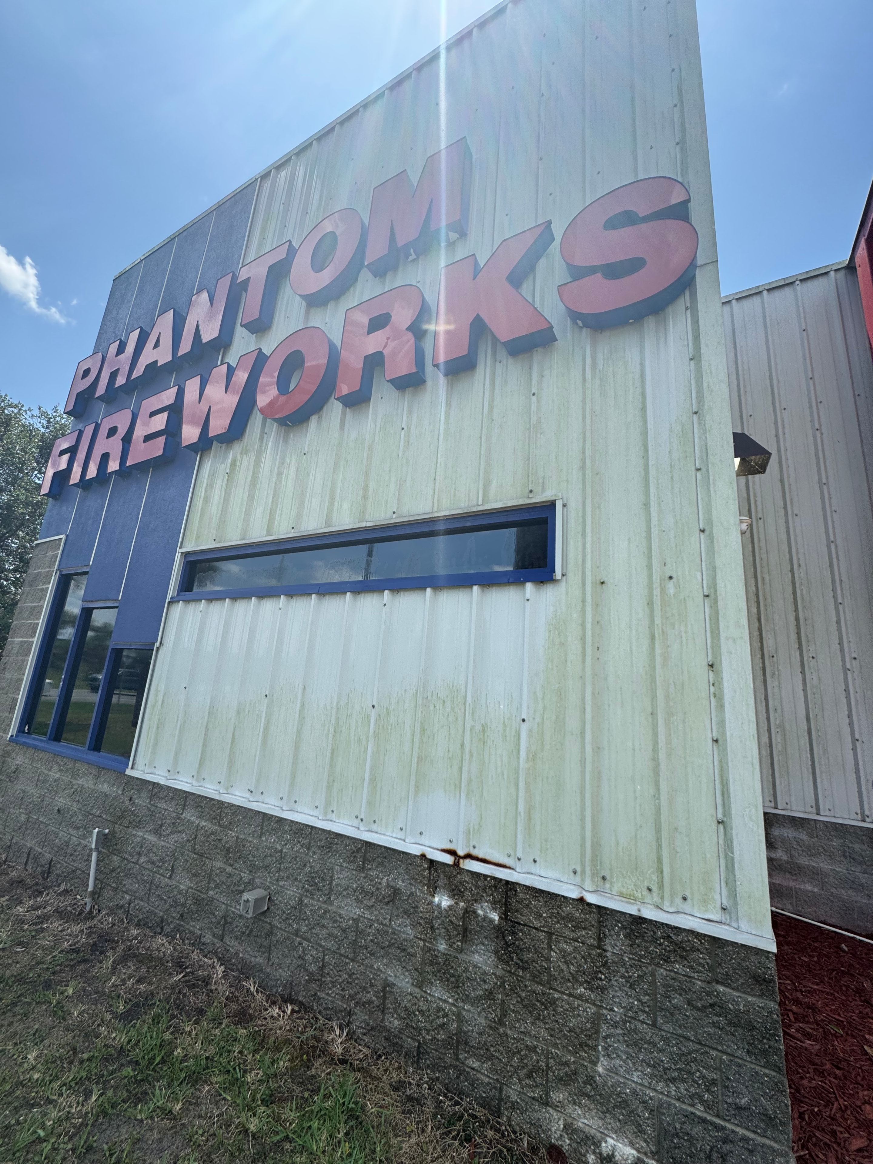 Phantom Fireworks commercial building exterior before pressure washing — heavy green algae on metal panel siding, Nocatee, Jacksonville, FL
