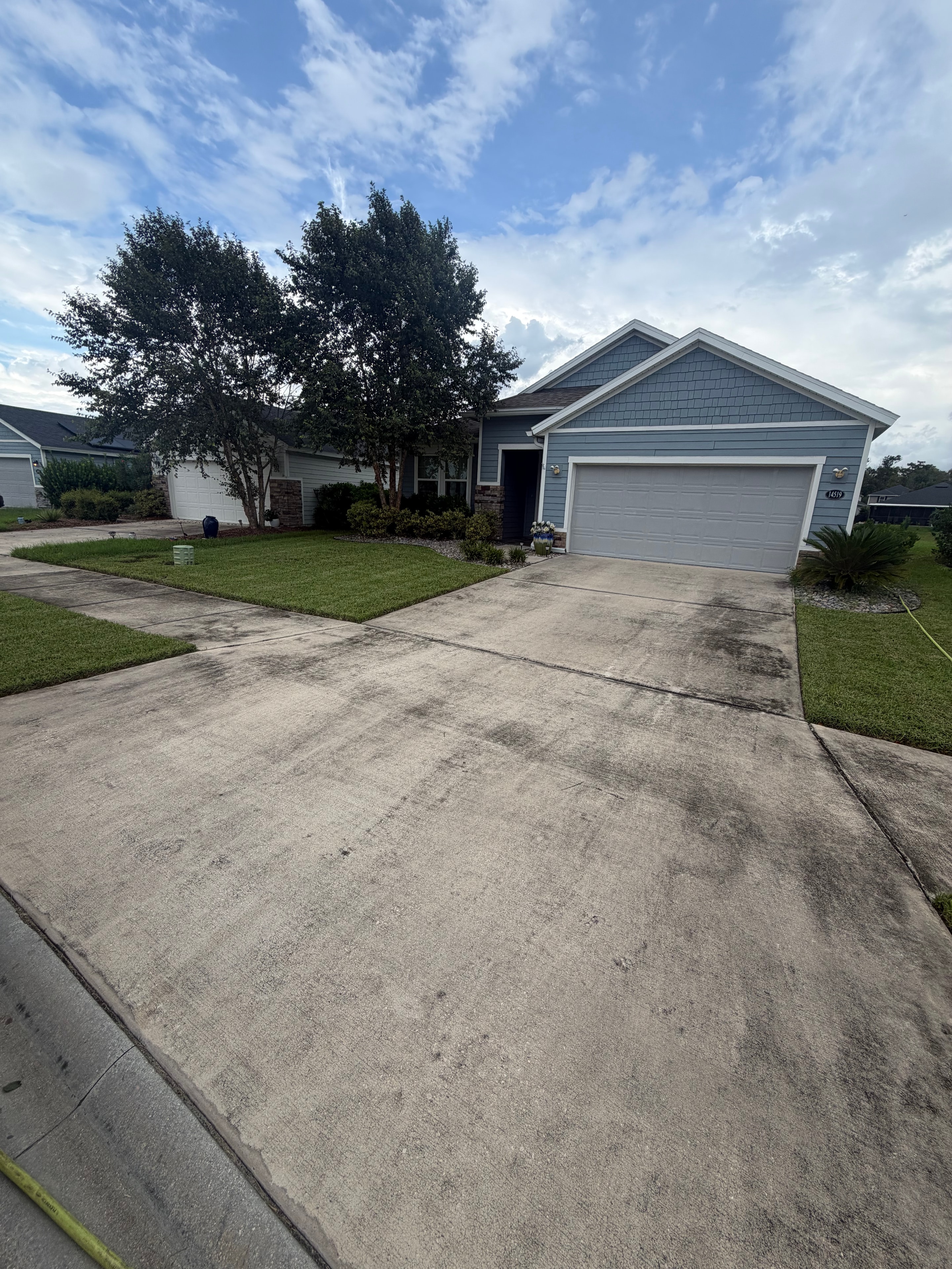 Residential driveway before pressure washing — dark grey stained and dirty concrete, Jacksonville, FL